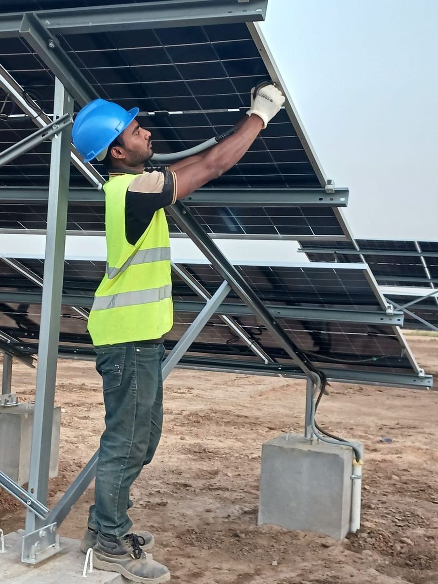 A technician mounting a solar panel at an SNA station